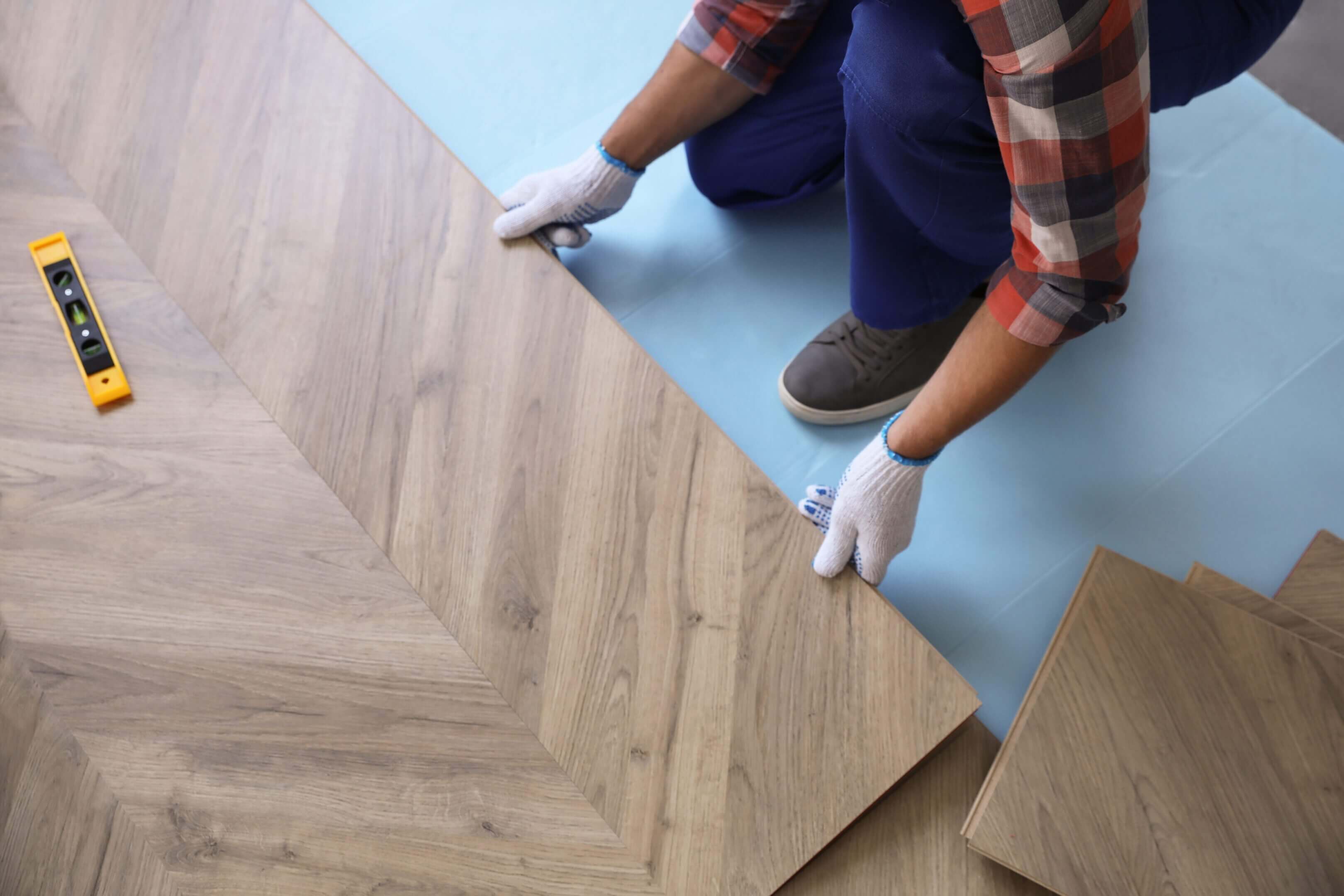 Person installing wood laminate flooring.